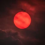 Eerie Red Sun Over British Columbia: Wildfire Smoke Transforms Our Star into an Exoplanet Vision, Revealing Active Sunspots